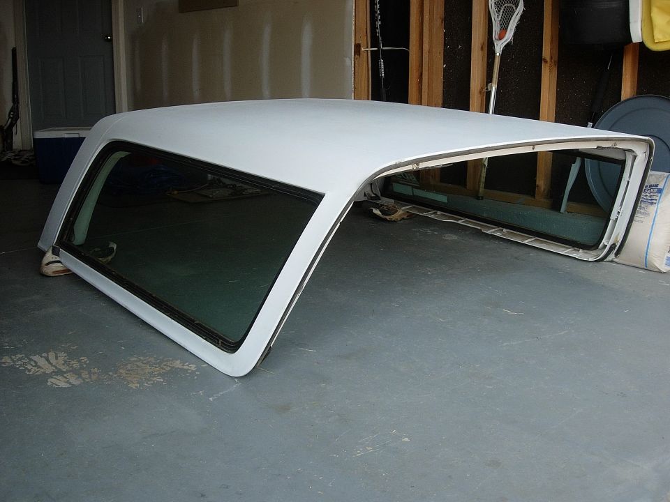 white car canopy with tinted windows, resting on a garage floor