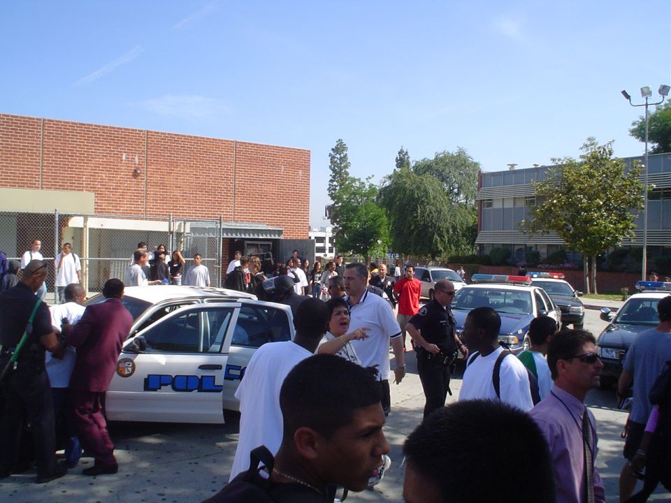 Police car with "POLICE" text on door, surrounded by people