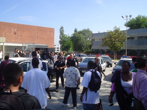1993 Ford Taurus - A group of police officers and civilians are seen gathered outdoors near several police vehicles.