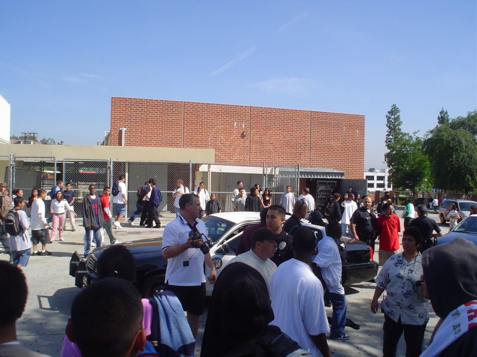 Police car parked in a crowd of people outside a brick building