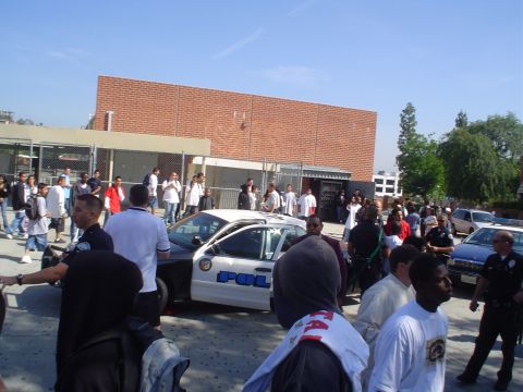 1993 Ford Taurus - A police car is visible amidst a gathering of people outside a brick building.
