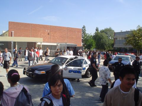 1993 Ford Taurus - Several police cars are present at a school with a large gathering of students and officers.