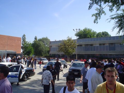 1993 Ford Taurus - Several police vehicles are present at an outdoor gathering of people near a brick building.