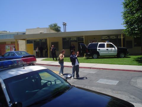 1993 Ford Taurus - Several vehicles, including a police SUV, are parked outside a building while people observe.