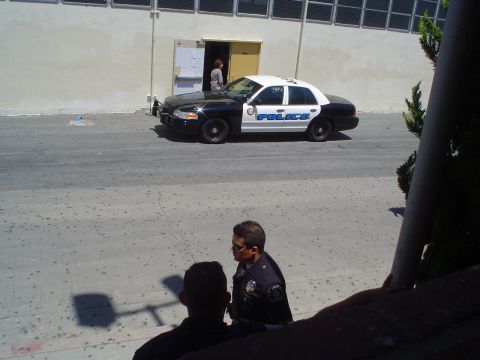 1993 Ford Taurus - A police car is parked on the street outside a building, with two officers visible in the foreground.