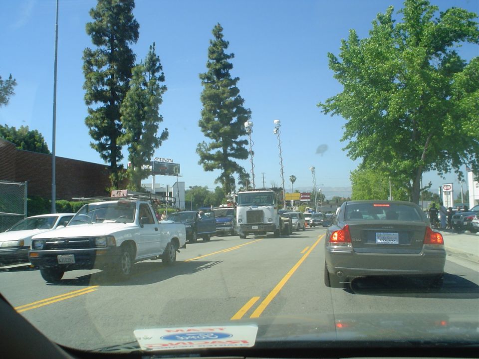 Traffic jam on a sunny day, view from inside a car. White pickup truck in foreground, followed by other cars and a large truck