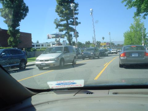 1993 Ford Taurus - A line of vehicles are stopped on a road under a clear blue sky.
