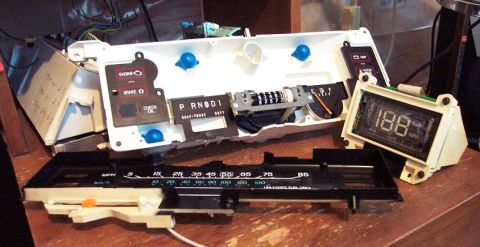 1985 Ford Crown Victoria LTD - Car dashboard instrument cluster disassembled, showing various gauges and a digital readout.