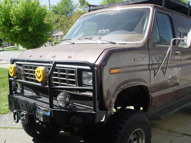 Brown 1980s Ford Econoline van with custom front winch bumper, brush guard and yellow off-road lights