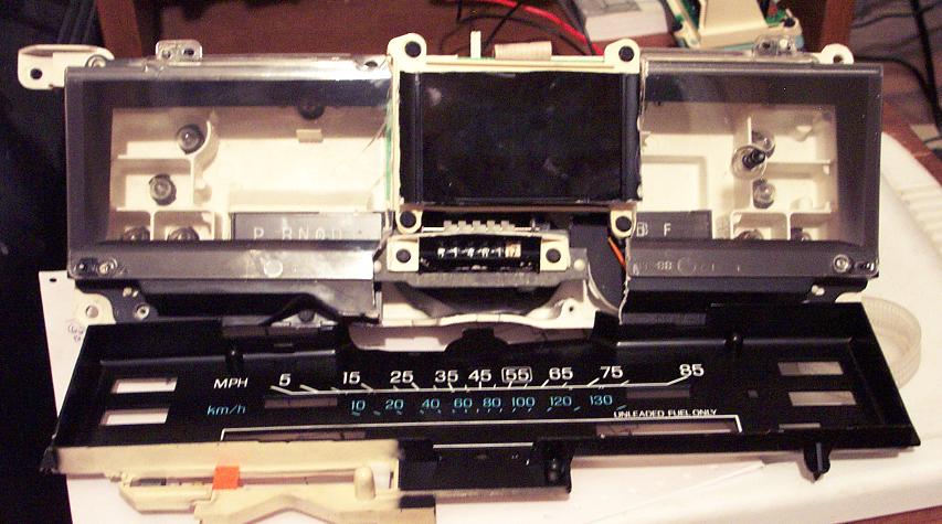 Car dashboard instrument cluster with speedometer, tachometer, and fuel gauge. Shows P R N D L gear indicator