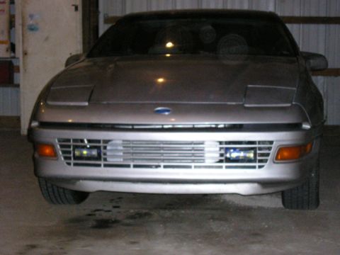 1990 Ford Probe - The front end of a 1990 Ford Probe is shown, its distinctive pop-up headlights and a wide horizontal grille.