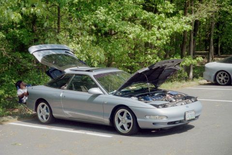 1995 Ford Probe - Two Ford Probes parked outdoors, one with its engine compartment and trunk open.