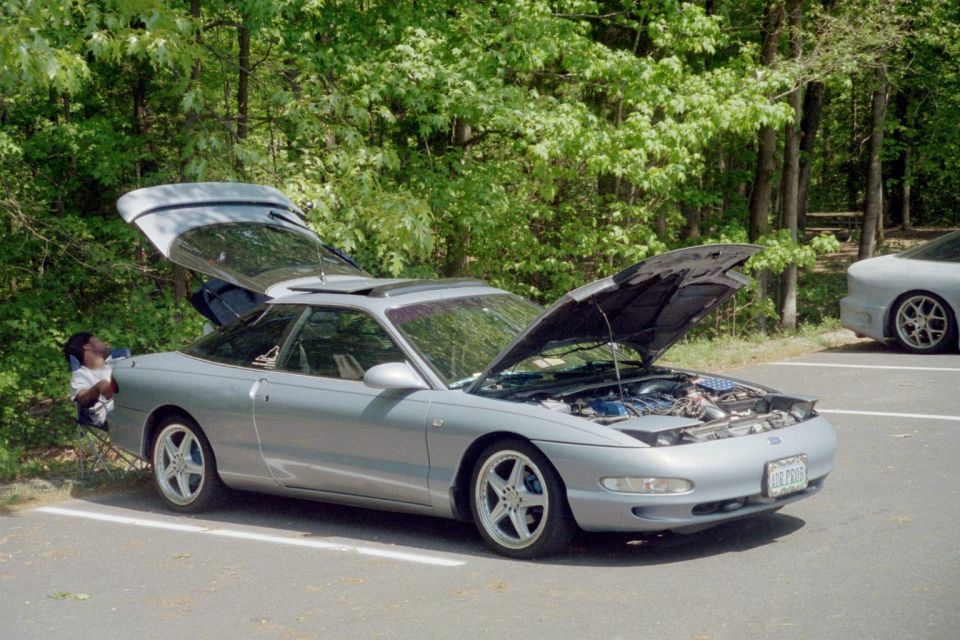 Silver 1995 Ford Probe with hood and trunk open, parked next to another Probe