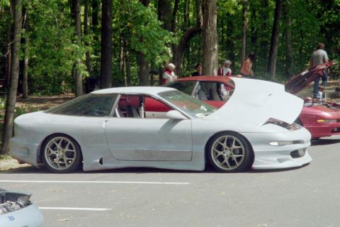 1995 Ford Probe - A gray Ford Probe is parked with its hood open, alongside another red car.