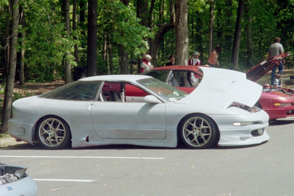 Gray Ford Probe with hood open, side view, aftermarket wheels, lowered suspension