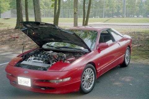 1995 Ford Probe - 1995 Ford Probe with its hood open, parked outdoors with trees in the background.