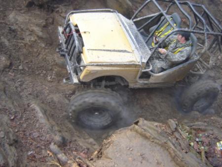 1989 Ford Bronco - This modified 1989 Ford Bronco navigates a steep, muddy incline with its driver wearing a camouflage uniform.