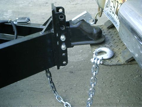 1979 Ford Bronco - Close-up of a trailer hitch mechanism and safety chains connected to a vehicle's rear.