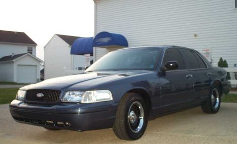 1998 Ford Crown Victoria - This 1998 Ford Crown Victoria is shown in a three-quarter front view, highlighting its dark blue paint and classic sedan body style.