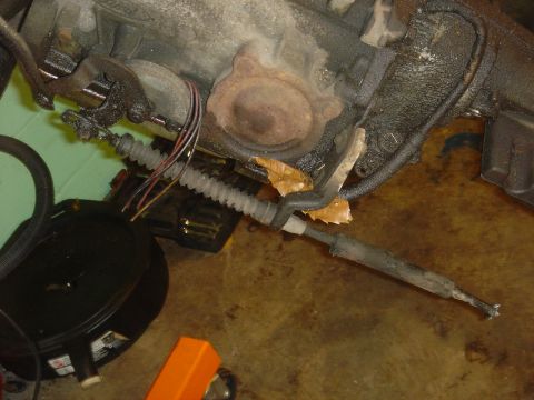 1986 Ford Mustang - Detail shot of a vehicle's transmission and associated cables, with a black oil pan in the foreground.