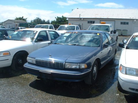 1999 Ford Crown Victoria - A blue sedan is parked in an outdoor lot with other vehicles.