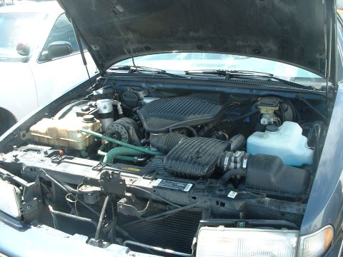 1999 Ford Crown Victoria - The engine bay of a dark blue car is shown with the hood open, revealing the engine components.