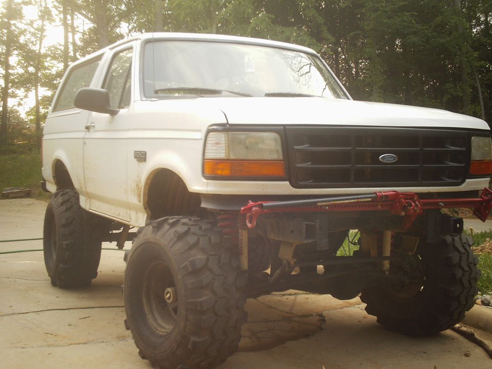 White lifted Ford Bronco on large mud tires, 3/4 front view on driveway