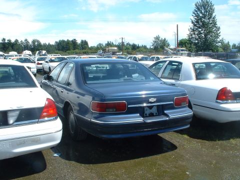 1999 Ford Crown Victoria - Rear view of a blue Chevrolet Caprice sedan in a parking lot with multiple vehicles.