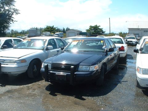 1999 Ford Crown Victoria - Several Ford Crown Victorias are parked in an outdoor lot, some with visible auction tags.