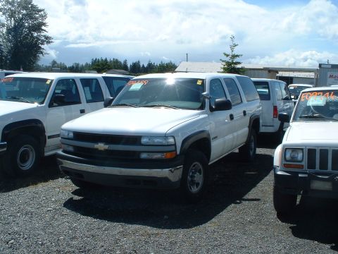 1999 Ford Crown Victoria - White Chevrolet Suburban from the front three-quarter view, parked outdoors with other vehicles.