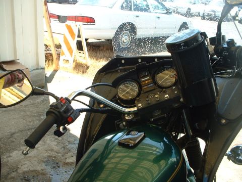 1999 Ford Crown Victoria - View of a motorcycle's interior controls and dashboard, with a white sedan visible behind a traffic barrier.