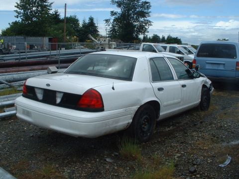 1999 Ford Crown Victoria - A white 1998 Ford Crown Victoria is parked in a lot with other vehicles and industrial materials visible.