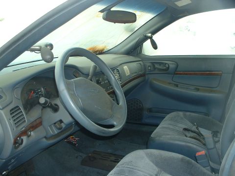 1999 Ford Crown Victoria - The interior of a car is visible, blue upholstery, a steering wheel, and the dashboard with an instrument cluster.