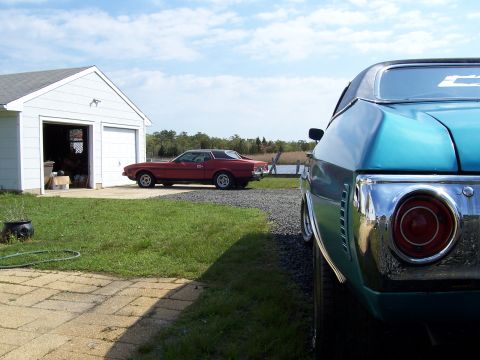 1971 Chevrolet Chevelle - A red coupe is parked in front of a garage, with a blue car in the foreground.