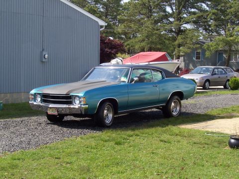 1971 Chevrolet Chevelle - This 1971 Chevrolet Chevelle coupe features a distinctive matte black hood stripe and a black vinyl roof, parked in a residential driveway.
