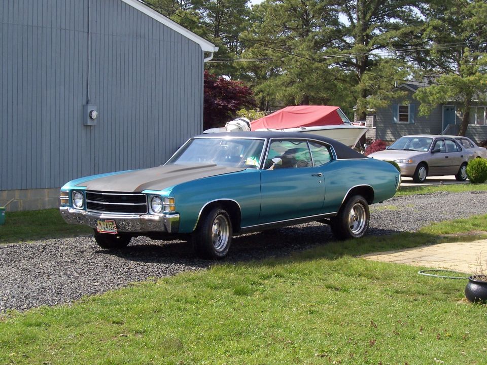 Teal 1971 Chevrolet Chevelle hardtop with primer hood on gravel driveway