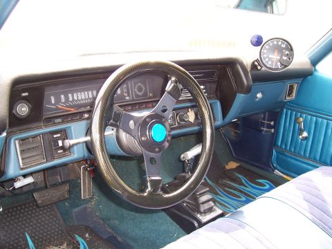 1971 Chevrolet Chevelle - The interior of a 1971 Chevrolet Chevelle features blue upholstery, a custom steering wheel, and flame-patterned floor mats.