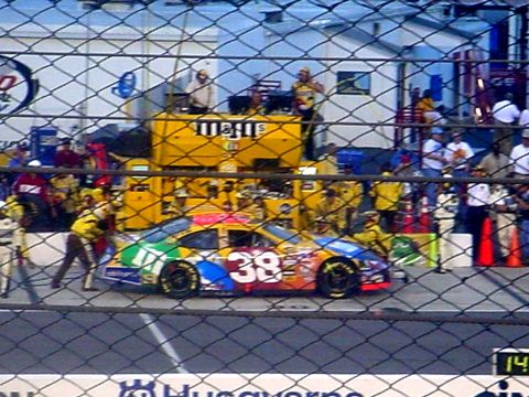 1973 Ford Ranchero - A colorful race car is being serviced in the pit stop area, with crew members attending to it.