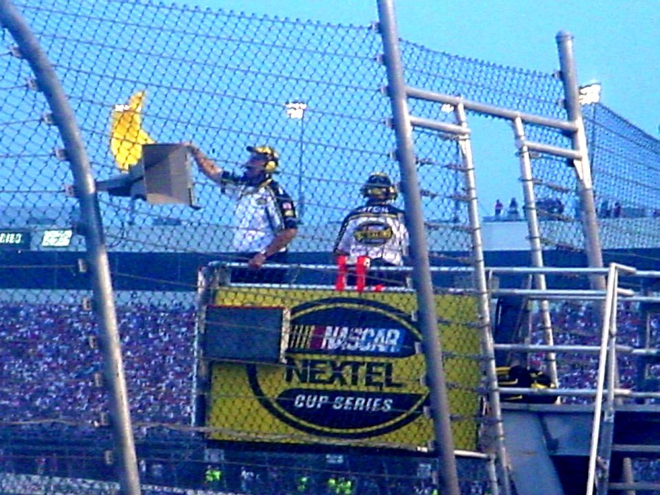 Flagman waving the yellow caution flag on a NASCAR Nextel Cup Series flag stand