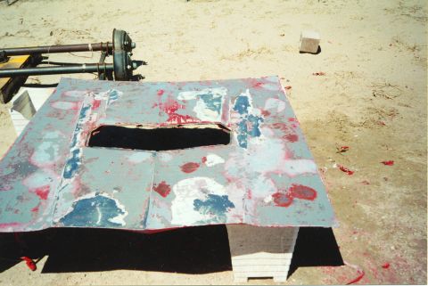 1972 Ford Ranchero - A car hood, stripped down and prepped for repair, sits outdoors on a sandy surface.