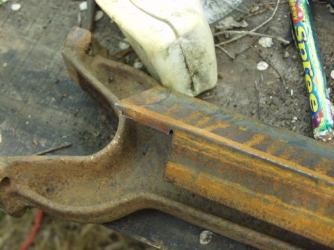 1979 Ford Bronco - A close-up view of a heavily rusted metal component, possibly from a vehicle, resting on a wooden surface.