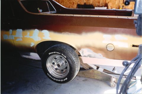 1972 Ford Ranchero - A 1972 Ford Ranchero is shown in a garage with visible body filler and sanding on its side panel.