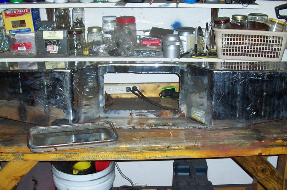 Chrome bumper with large cutout and a separate trim piece on a workbench