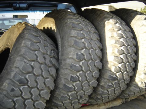 1988 Ford Bronco - Several large off-road tires are loaded into the back of a vehicle, with the "Cooper" brand visible on one.