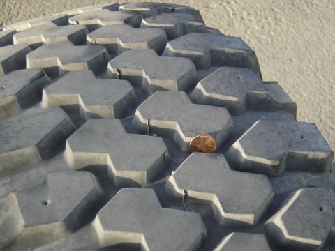 1988 Ford Bronco - A penny rests in the deep grooves of a heavy-duty tire, highlighting its substantial tread.