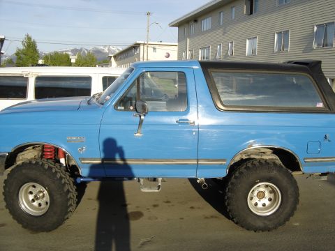 1988 Ford Bronco - This blue Ford Bronco is shown from the side, lifted with large tires and a black removable top.