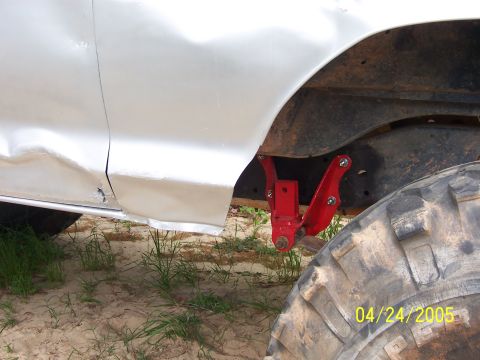 1978 Ford Bronco - A red shackle flip suspension component is visible on a white vehicle with significant body damage.