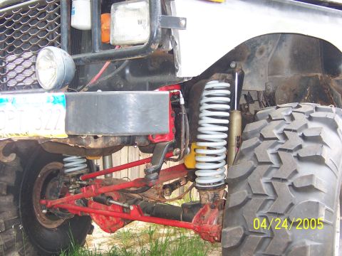 1978 Ford Bronco - Close-up view of the modified suspension system and front tire of an off-road vehicle.