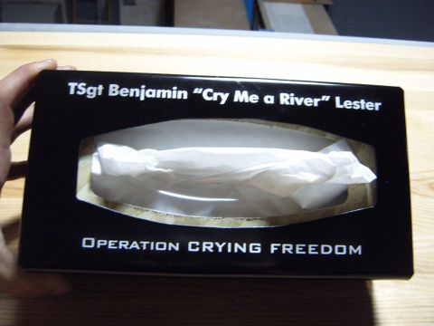 1988 Ford Bronco - A black tissue box with personalized text is held by a hand over a wooden surface.