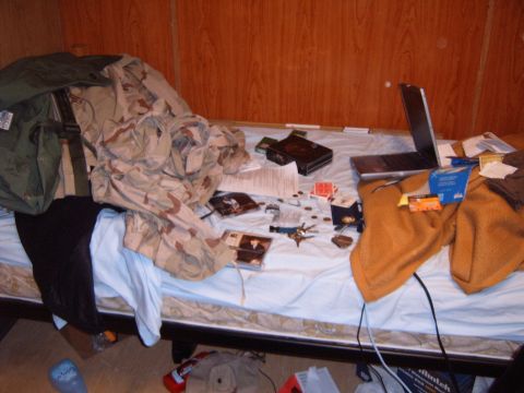 1988 Ford Bronco - A cluttered bed displays various personal belongings, including clothing, a laptop, and what appear to be CDs and playing cards.